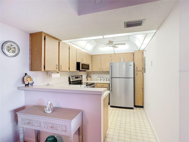 kitchen with ceiling fan, light brown cabinets, kitchen peninsula, a textured ceiling, and appliances with stainless steel finishes