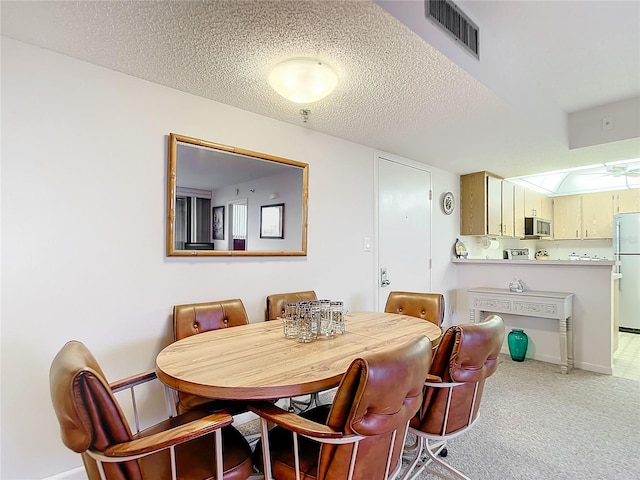 carpeted dining space with a textured ceiling