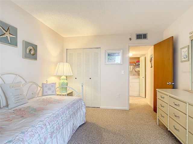 carpeted bedroom with washer / dryer, a textured ceiling, and a closet