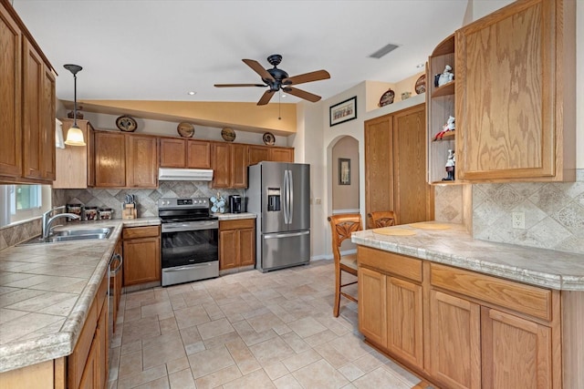 kitchen featuring pendant lighting, vaulted ceiling, ceiling fan, decorative backsplash, and stainless steel appliances