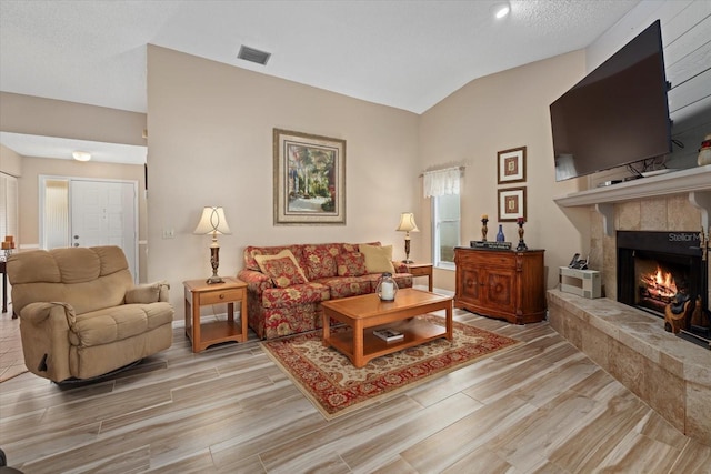 living room featuring a tiled fireplace and vaulted ceiling