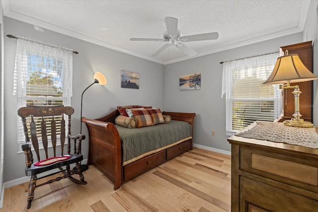 bedroom featuring ceiling fan, light wood-type flooring, ornamental molding, and a textured ceiling