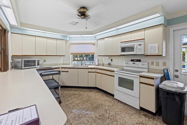 kitchen featuring white appliances, sink, ceiling fan, a textured ceiling, and cream cabinetry