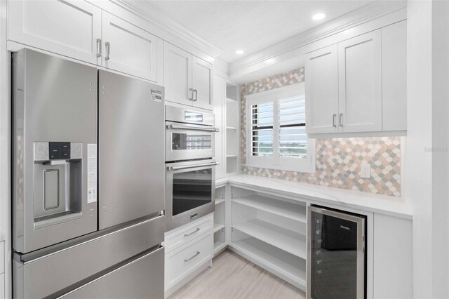 kitchen with stainless steel appliances, beverage cooler, and white cabinets