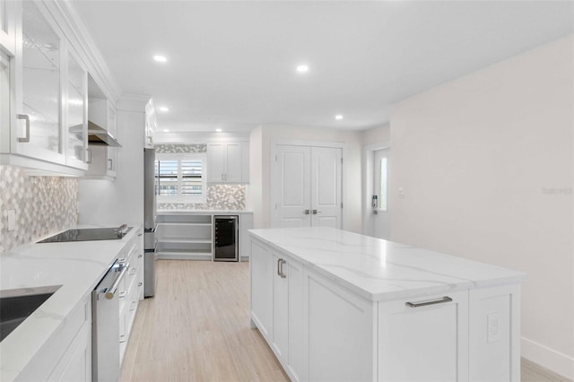 kitchen featuring white cabinets, beverage cooler, backsplash, light stone counters, and black electric cooktop