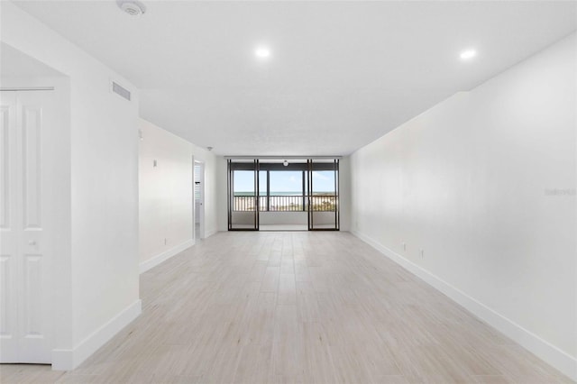 empty room featuring light wood-type flooring and a wall of windows