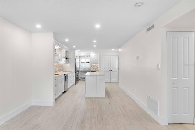 kitchen with white cabinetry, tasteful backsplash, stainless steel refrigerator, a kitchen island, and light hardwood / wood-style flooring