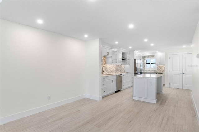 kitchen featuring decorative backsplash, sink, white cabinetry, and a center island