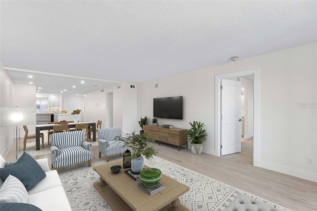 living room with a textured ceiling and light hardwood / wood-style flooring