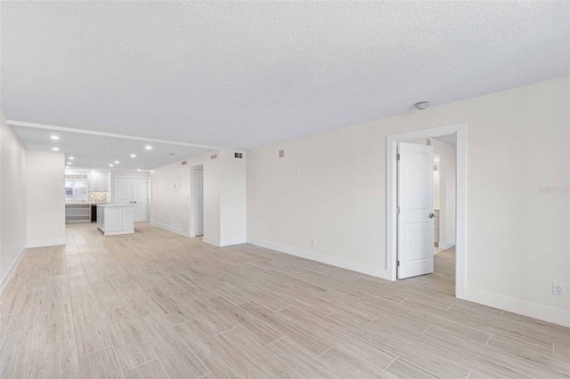 unfurnished living room featuring a textured ceiling and light hardwood / wood-style flooring