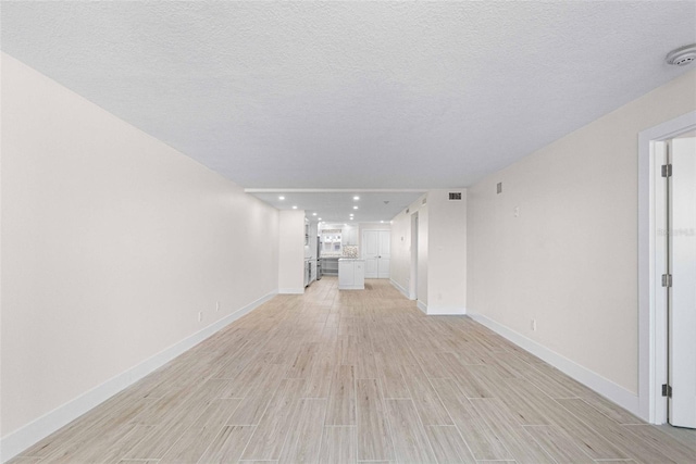 unfurnished living room with a textured ceiling and light hardwood / wood-style floors