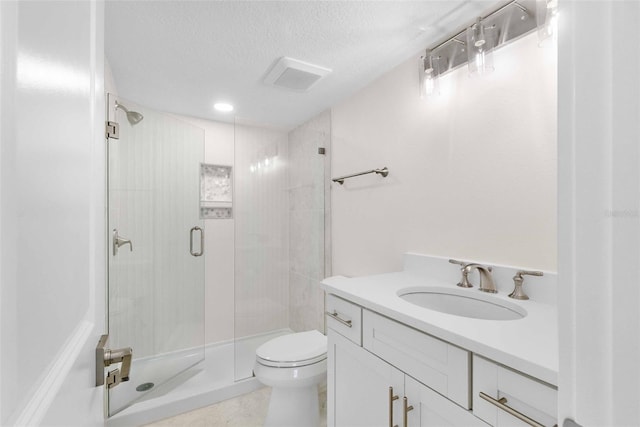 bathroom with a textured ceiling, toilet, a shower with shower door, and vanity