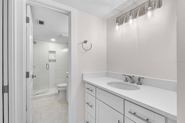 bathroom featuring a textured ceiling, toilet, a shower with door, and vanity