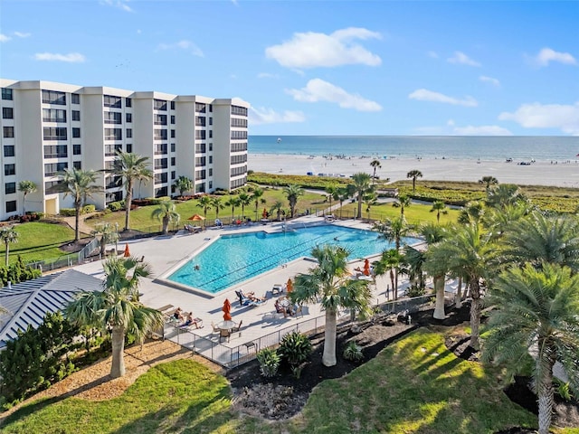 view of swimming pool with a water view, a patio area, and a view of the beach