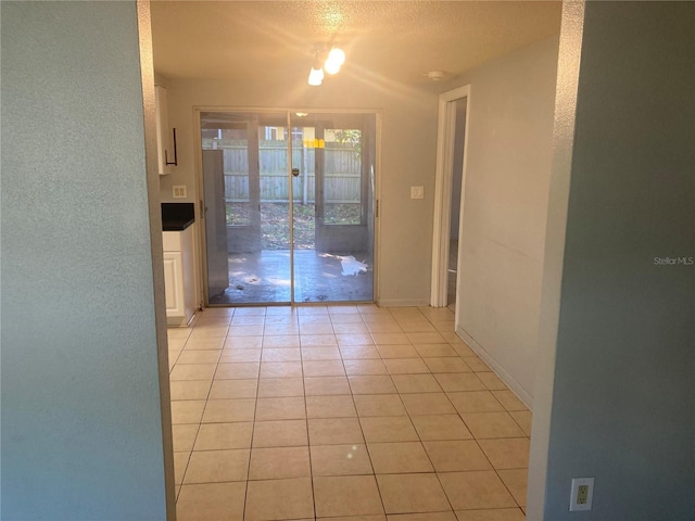 interior space with a textured ceiling and light tile patterned flooring