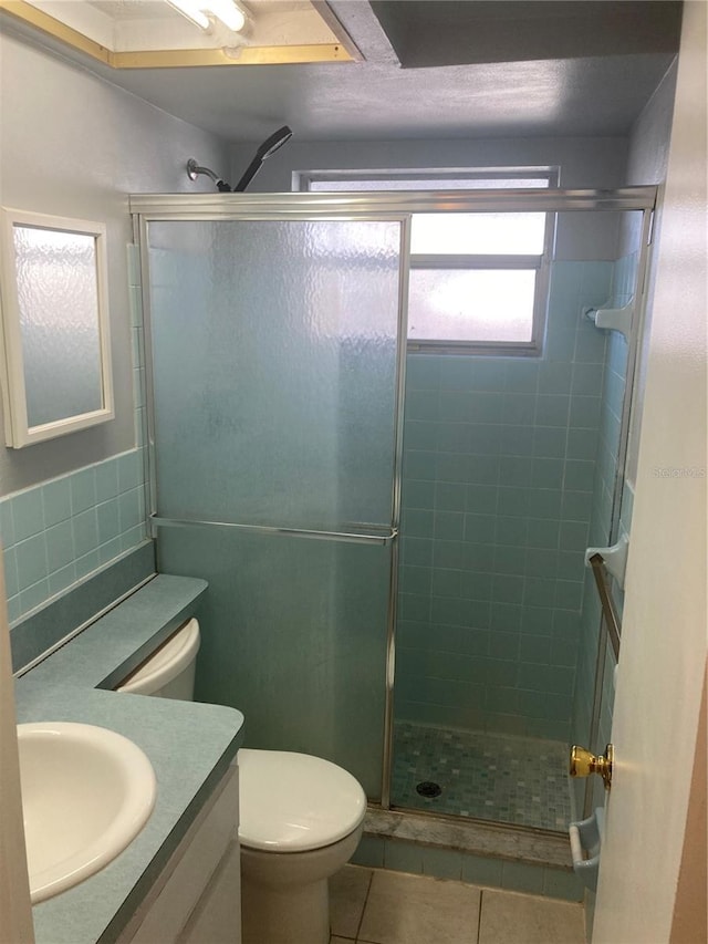 bathroom featuring toilet, vanity, tile patterned floors, and an enclosed shower