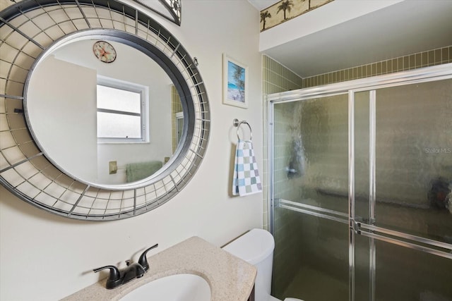 bathroom with a shower with door, vanity, and toilet