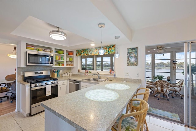 kitchen with a water view, sink, ceiling fan, kitchen peninsula, and stainless steel appliances