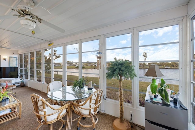 sunroom featuring ceiling fan, a healthy amount of sunlight, and a water view