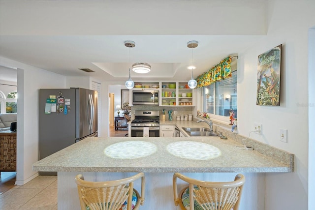 kitchen with a breakfast bar, pendant lighting, stainless steel appliances, and sink