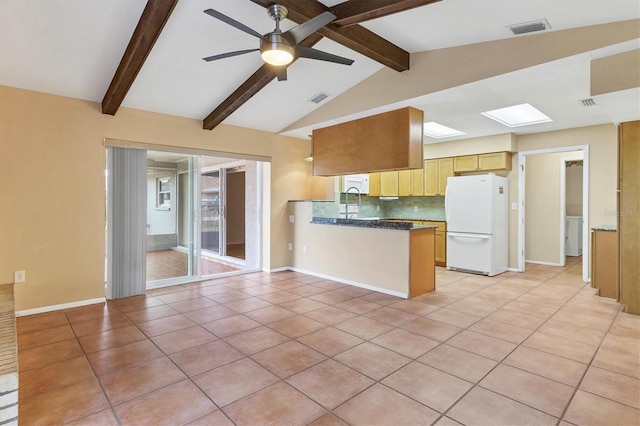 kitchen featuring tasteful backsplash, light tile patterned floors, lofted ceiling with beams, and white refrigerator