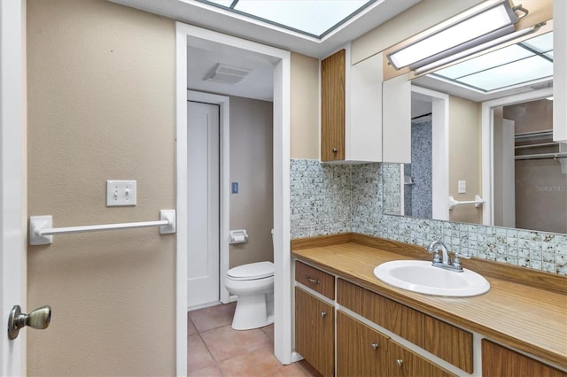 bathroom featuring toilet, vanity, backsplash, and tile patterned floors