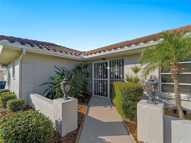 view of exterior entry featuring a tiled roof and stucco siding