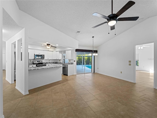 kitchen with lofted ceiling, appliances with stainless steel finishes, light tile patterned floors, and white cabinets