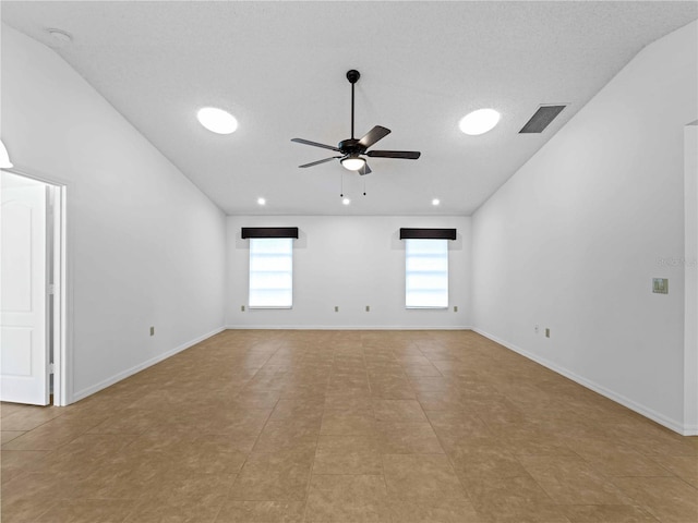 unfurnished room with ceiling fan, vaulted ceiling, visible vents, and baseboards