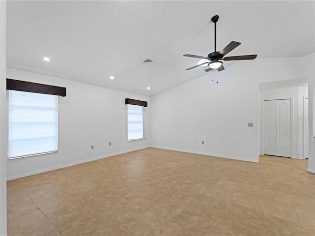 empty room with a ceiling fan, visible vents, vaulted ceiling, and baseboards