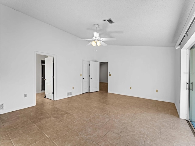 spare room with lofted ceiling, a textured ceiling, and visible vents