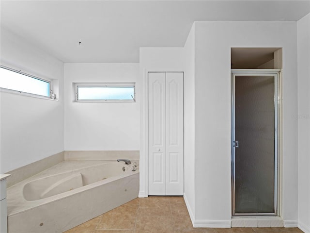 bathroom with tile patterned flooring, baseboards, a closet, a bath, and a stall shower