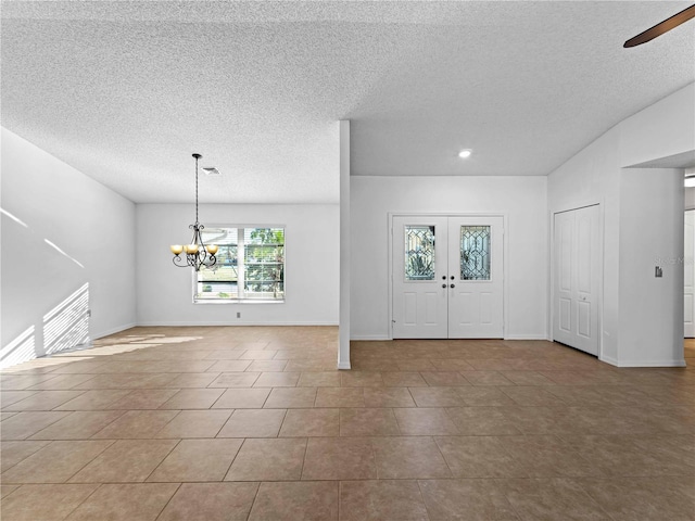 tiled foyer with a textured ceiling, french doors, visible vents, and baseboards