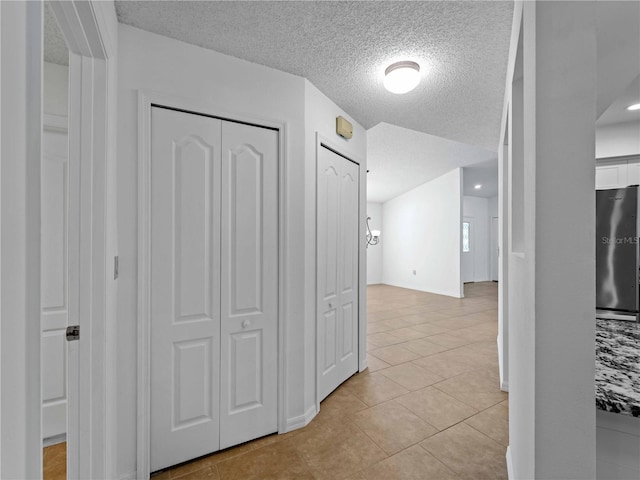 hall featuring light tile patterned floors and a textured ceiling