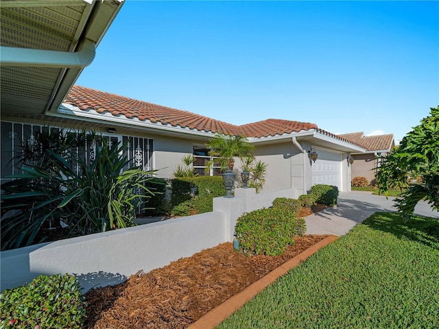 view of side of property featuring a garage, a tiled roof, and stucco siding