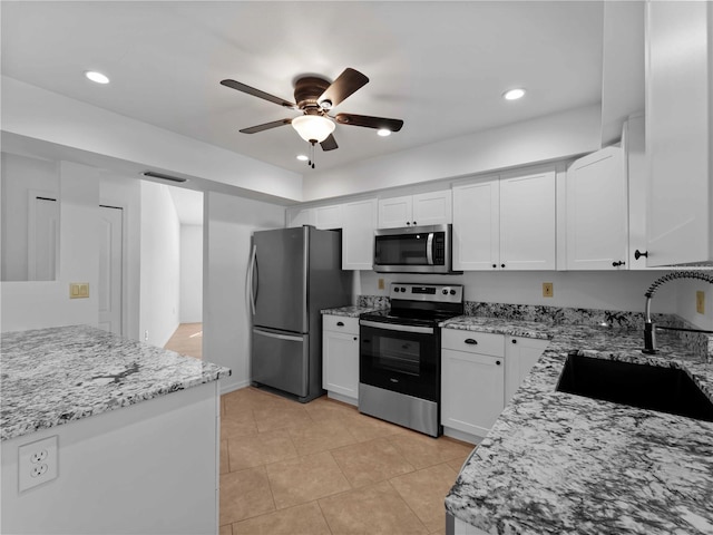 1678 Quail Lake Dr, Venice, FL 34293 - kitchen with stainless steel appliances, a sink, a ceiling fan, light stone counters, and white cabinetry