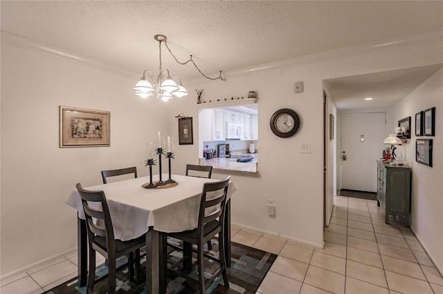 dining room featuring a textured ceiling, light tile patterned floors, ornamental molding, and a chandelier