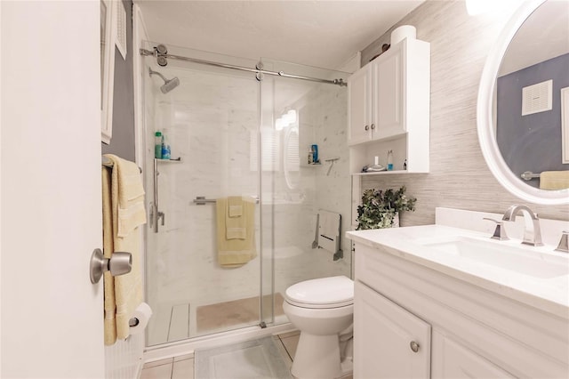 bathroom with tile patterned floors, vanity, toilet, and a shower with door