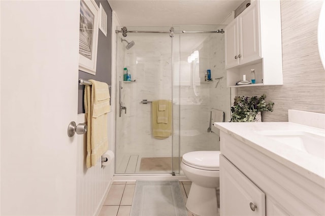 bathroom featuring tile patterned floors, a shower with door, vanity, and toilet