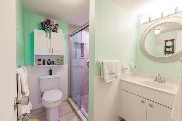 bathroom featuring tile patterned floors, a textured ceiling, toilet, vanity, and a shower with shower door