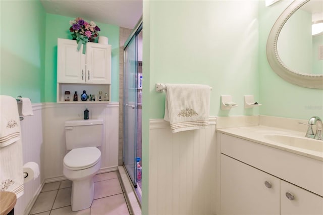 bathroom featuring tile patterned flooring, vanity, toilet, and a shower with shower door