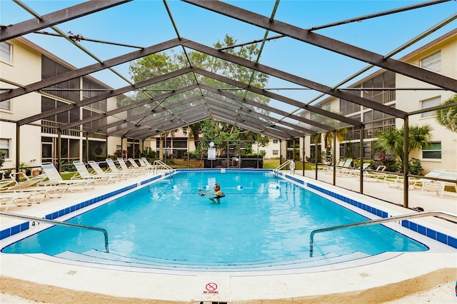 view of swimming pool with glass enclosure and a patio