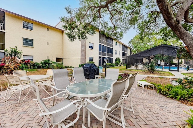 view of patio / terrace featuring glass enclosure, a community pool, and a grill