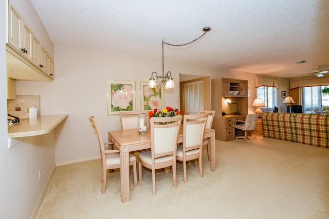 dining room with a notable chandelier, light colored carpet, and a textured ceiling