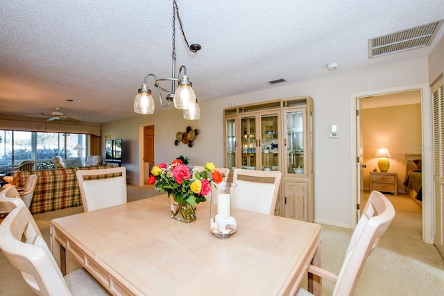 dining space featuring a textured ceiling, ceiling fan with notable chandelier, and light carpet