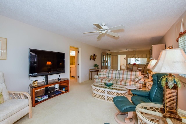 living room featuring ceiling fan, a textured ceiling, and light carpet