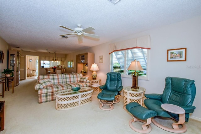 carpeted living room with ceiling fan with notable chandelier and a textured ceiling