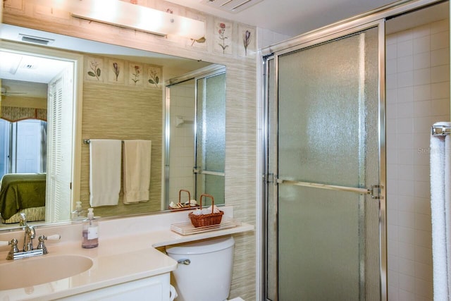 bathroom featuring a shower with door, vanity, and toilet