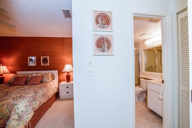 tiled bedroom with a textured ceiling, connected bathroom, and ceiling fan