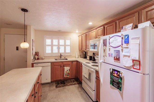 kitchen with decorative light fixtures, white appliances, and sink